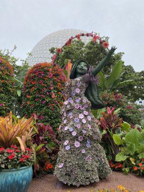 Encanto's Isabella made of flowers in front of trees and Spaceship Earth