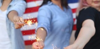 TOP 10 Tips for Fireworks Safety Alondra Olivas via Unsplash three women hold sparklers with an American flag behind them