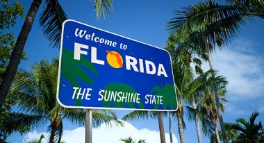 Welcome to Florida sign with palm trees behind it