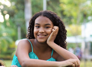 Dark brown girl teen with dark hair smiling and staring into the camera.