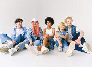 5 tween to teen-age children sitting down staring at camera laughing for a puberty survival guide for parents