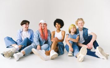 5 tween to teen-age children sitting down staring at camera laughing for a puberty survival guide for parents