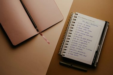 blank journal with pen and another journal with a list of new year's resolutions