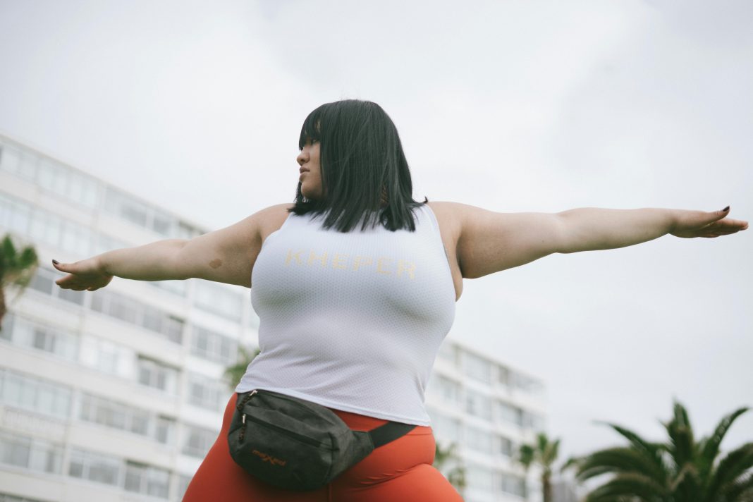 woman in a yoga position, outside with a building in the background. new year's resolutions