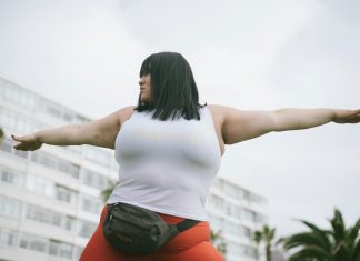 woman in a yoga position, outside with a building in the background. new year's resolutions