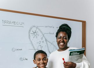 woman and child standing in front of a white board with a science lesson on it smiling at the camera. All to help kids thrive at school