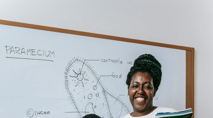 woman and child standing in front of a white board with a science lesson on it smiling at the camera. All to help kids thrive at school