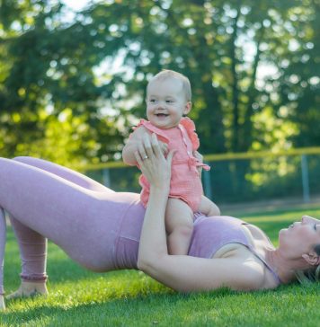 mom in workout clothes outside with baby on top of her, working out together finding gyms with childcare