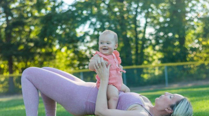 mom in workout clothes outside with baby on top of her, working out together finding gyms with childcare