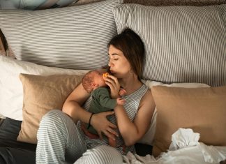 mom cuddling newborn baby in bed. Beauty and Wellness Tips for Postpartum Recovery