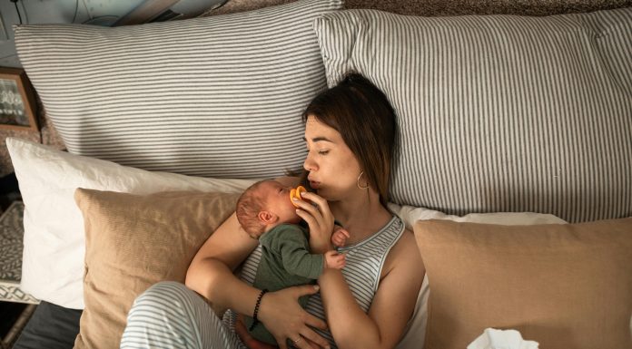 mom cuddling newborn baby in bed. Beauty and Wellness Tips for Postpartum Recovery