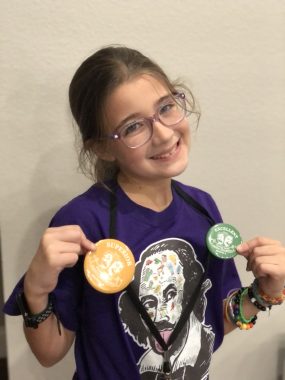 young girl showing medals and smiling at the camera