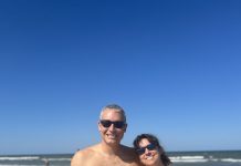 man and woman in bathing suits at the beach smiling at the camera