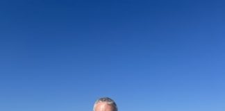 man and woman in bathing suits at the beach smiling at the camera