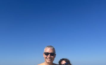 man and woman in bathing suits at the beach smiling at the camera