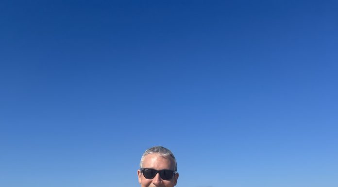 man and woman in bathing suits at the beach smiling at the camera