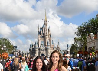 two women smiling at camera in front of Cinderella's castle in Disney World Orlando. On a girls trip