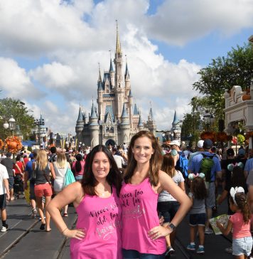 two women smiling at camera in front of Cinderella's castle in Disney World Orlando. On a girls trip