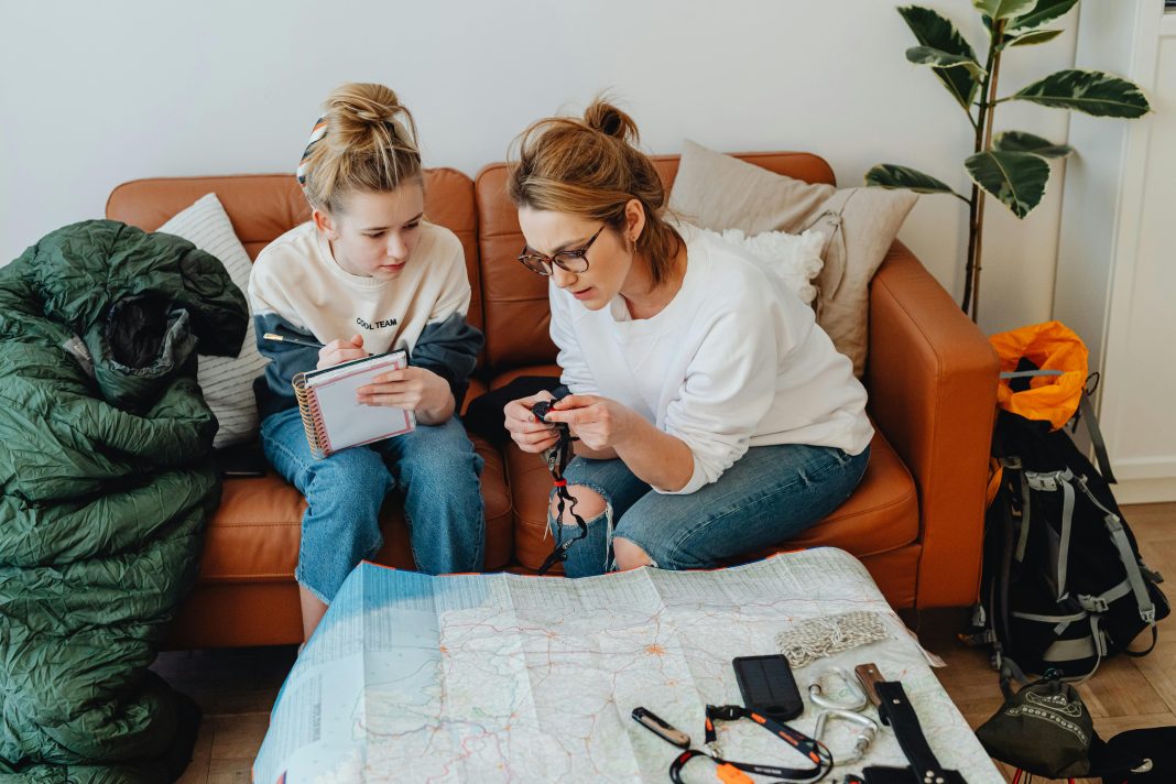 mom and daughter looking at a map and writing notes down for a pre travel checklist