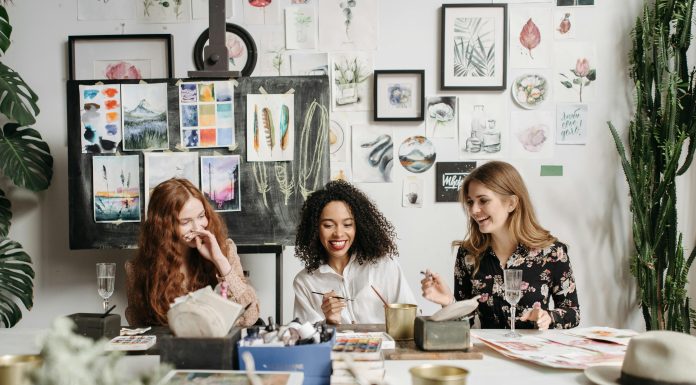 three women staring at a painting and smiling and laughing.