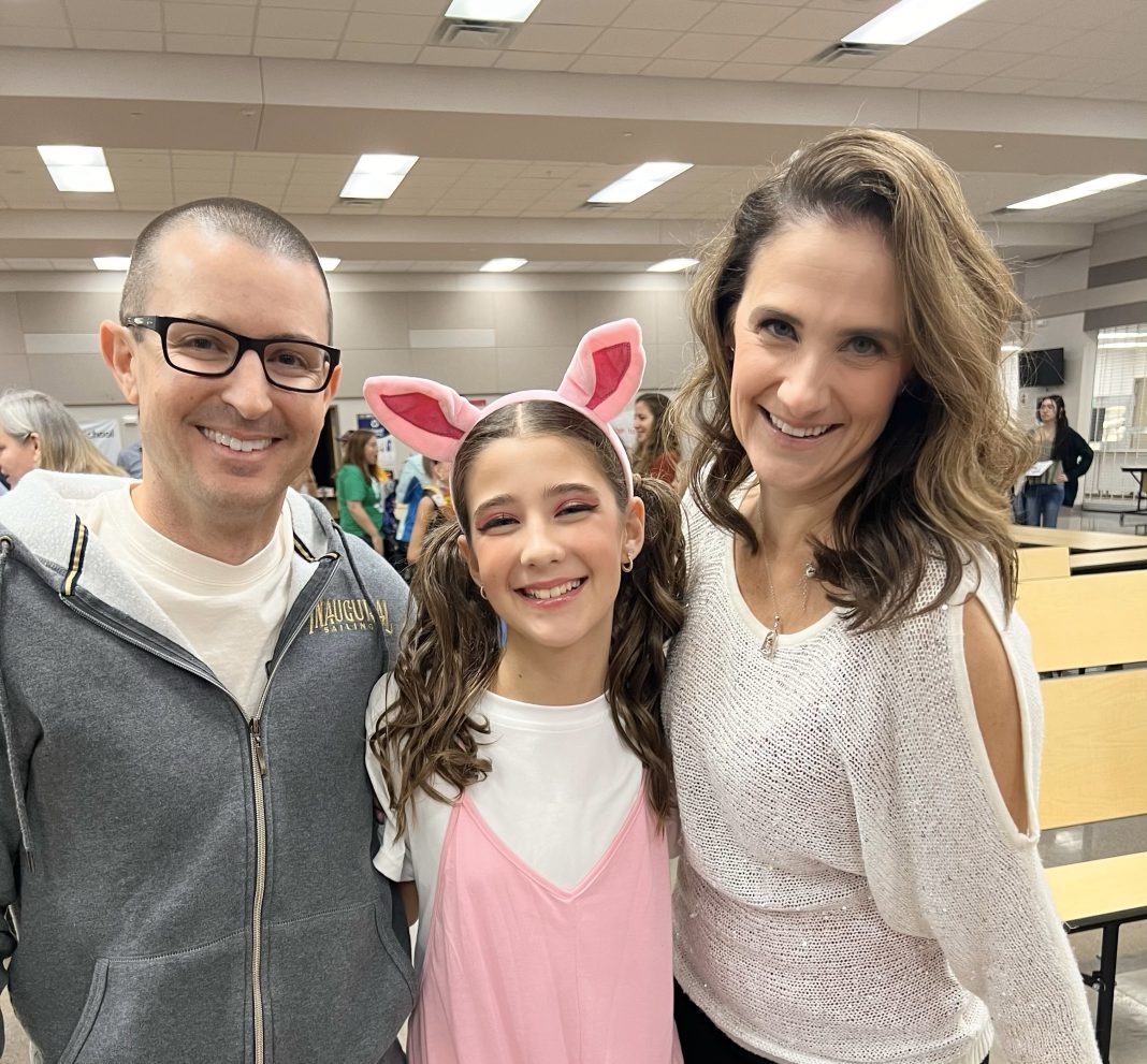 a mom, dad, and daughter staring at the camera smiling.