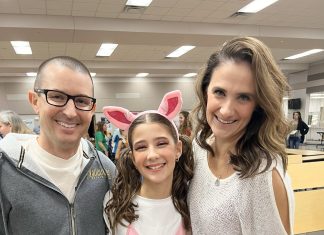 a mom, dad, and daughter staring at the camera smiling.