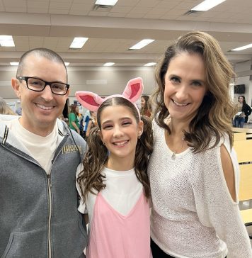 a mom, dad, and daughter staring at the camera smiling.