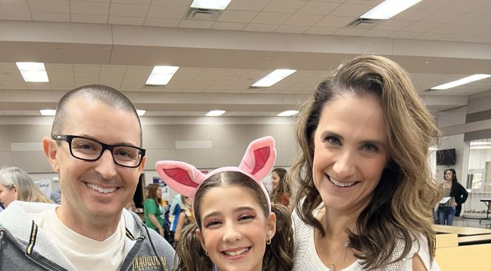 a mom, dad, and daughter staring at the camera smiling.