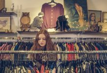 woman sorrounded by a clothing rack in a consignment store, consign in orlando