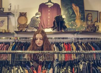 woman sorrounded by a clothing rack in a consignment store, consign in orlando