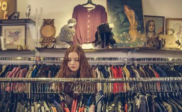 Places to Consign in Orlando woman sorrounded by a clothing rack in a consignment store, consign in orlando