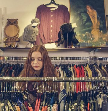 woman sorrounded by a clothing rack in a consignment store, consign in orlando