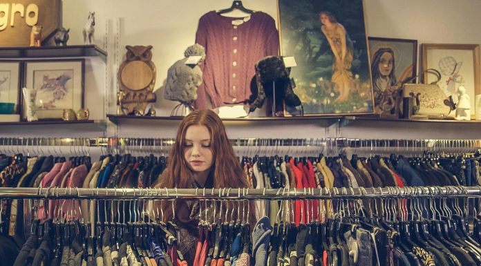 woman sorrounded by a clothing rack in a consignment store, consign in orlando