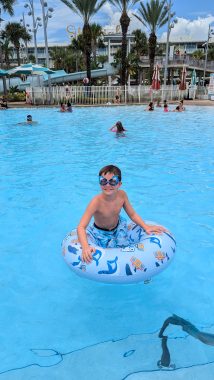 young boy in a pool float in the pool smiling at the camera