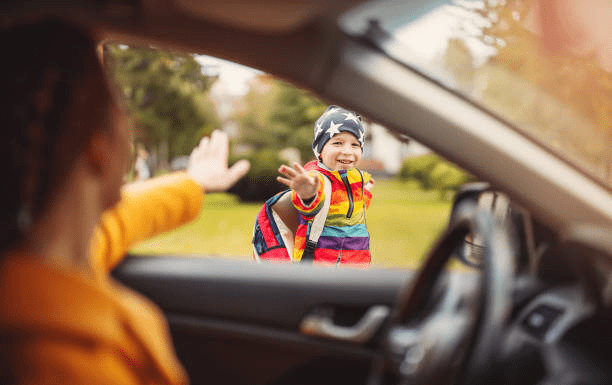 mom waving goodbye to child, a boy, boy smiling and waving back; back to school mom mental health