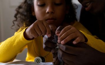 introducing kids to sewing: a young girl sewing a stuffed animal with parent