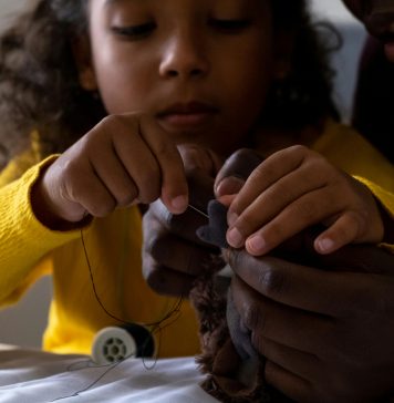 introducing kids to sewing: a young girl sewing a stuffed animal with parent