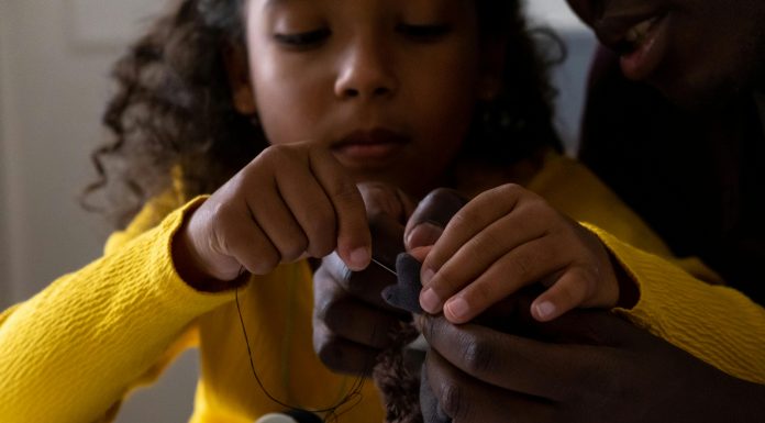 introducing kids to sewing: a young girl sewing a stuffed animal with parent