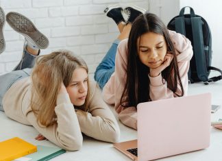 two girls laying down on the ground looking at a laptop transition to high school