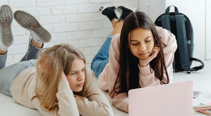 two girls laying down on the ground looking at a laptop transition to high school