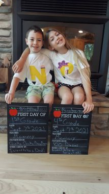 two children on their first day of homeschooling smiling at the camera
