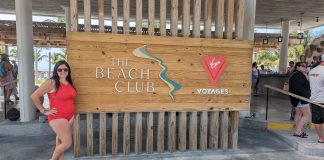 Why an Adult-Only Cruise with Virgin Voyages is Your Next Perfect Vacation woman standing next to a sign that says "the beach club". She smiling enjoying her adult-only cruise