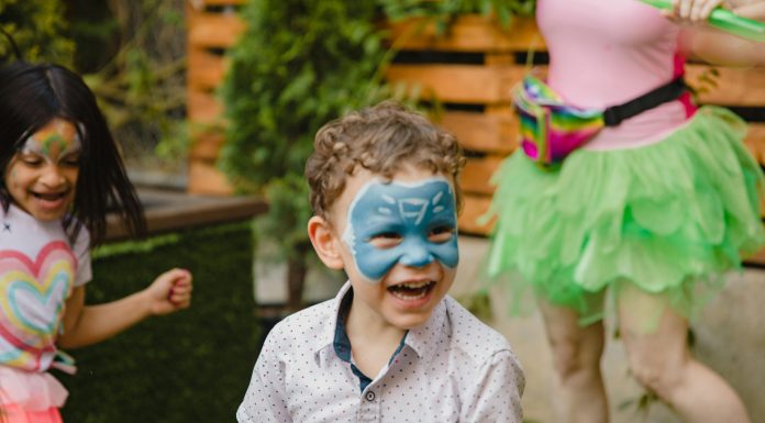 a young by with a painted face smiling look off to the side from the camera, for a safe and fun playdate ideas