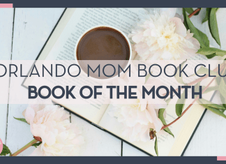 black coffee in white mug on open book with flowers and leaves on stems on the book and white table below book