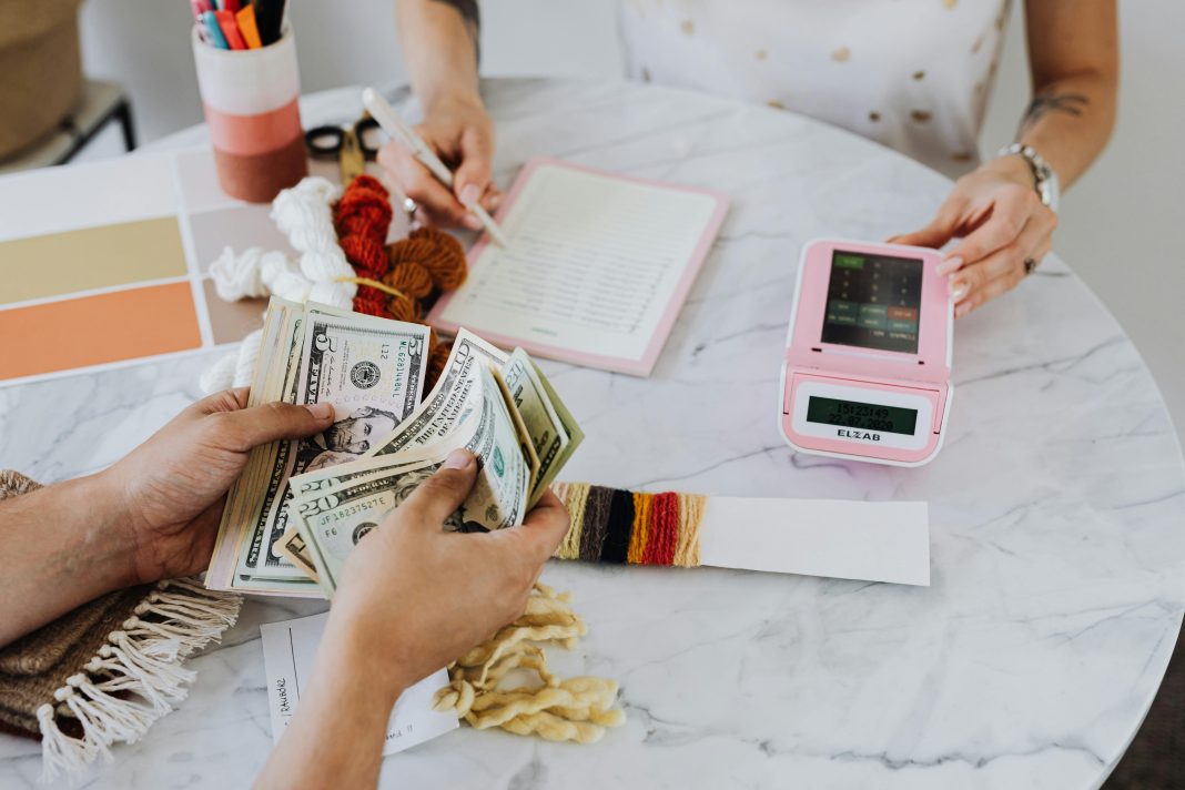 two people at a table with calculator and money, budgeting to financial freedom