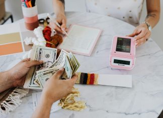 two people at a table with calculator and money, budgeting to financial freedom