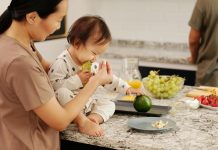 child on kitchen counter eating avocados with mom