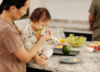 child on kitchen counter eating avocados with mom