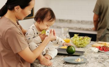 child on kitchen counter eating avocados with mom