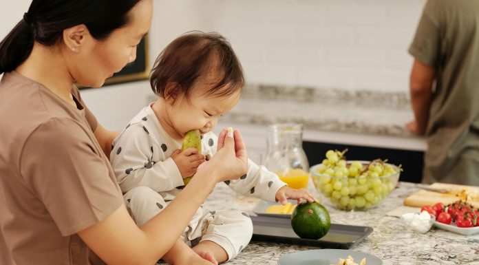 child on kitchen counter eating avocados with mom